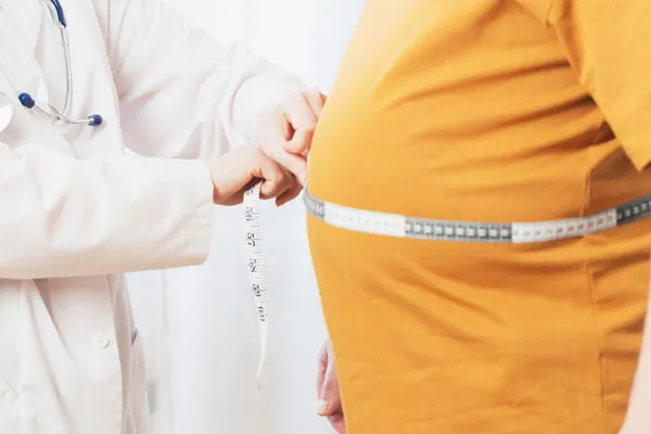 A doctor measuring a man’s waist in a clinic